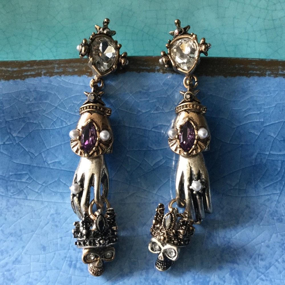 Dangle Hands holding Skull Treasure earrings.